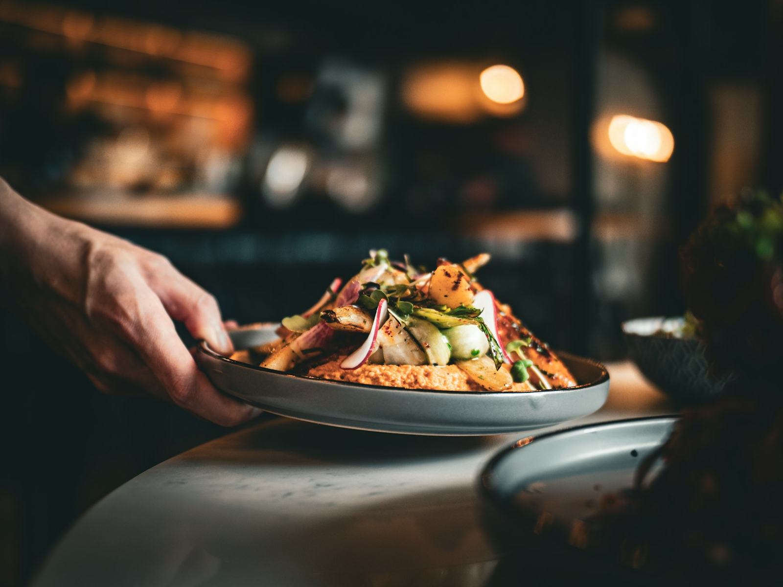 Server carrying a plated dish through the dining room